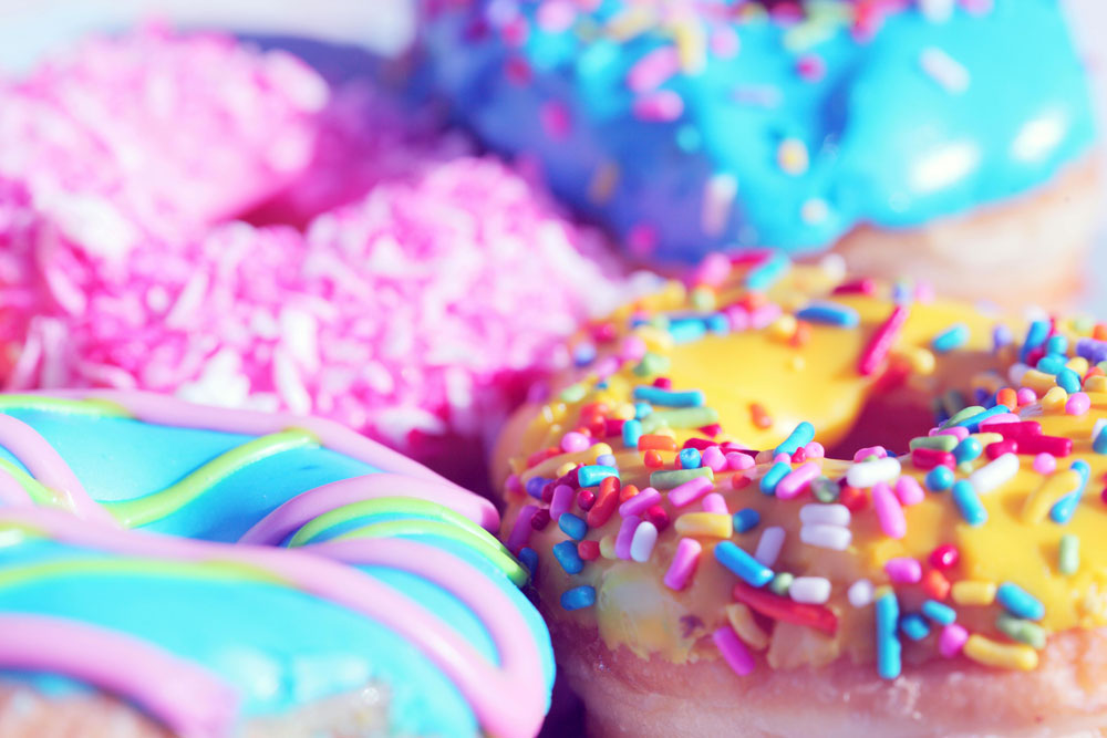 A close up of some colourful glazed donuts with sprinkles on
