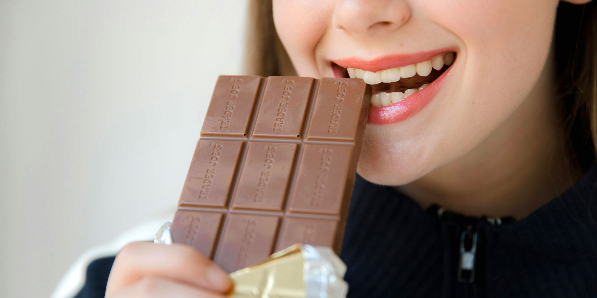 A close up of someone biting into a large bar of chocolate