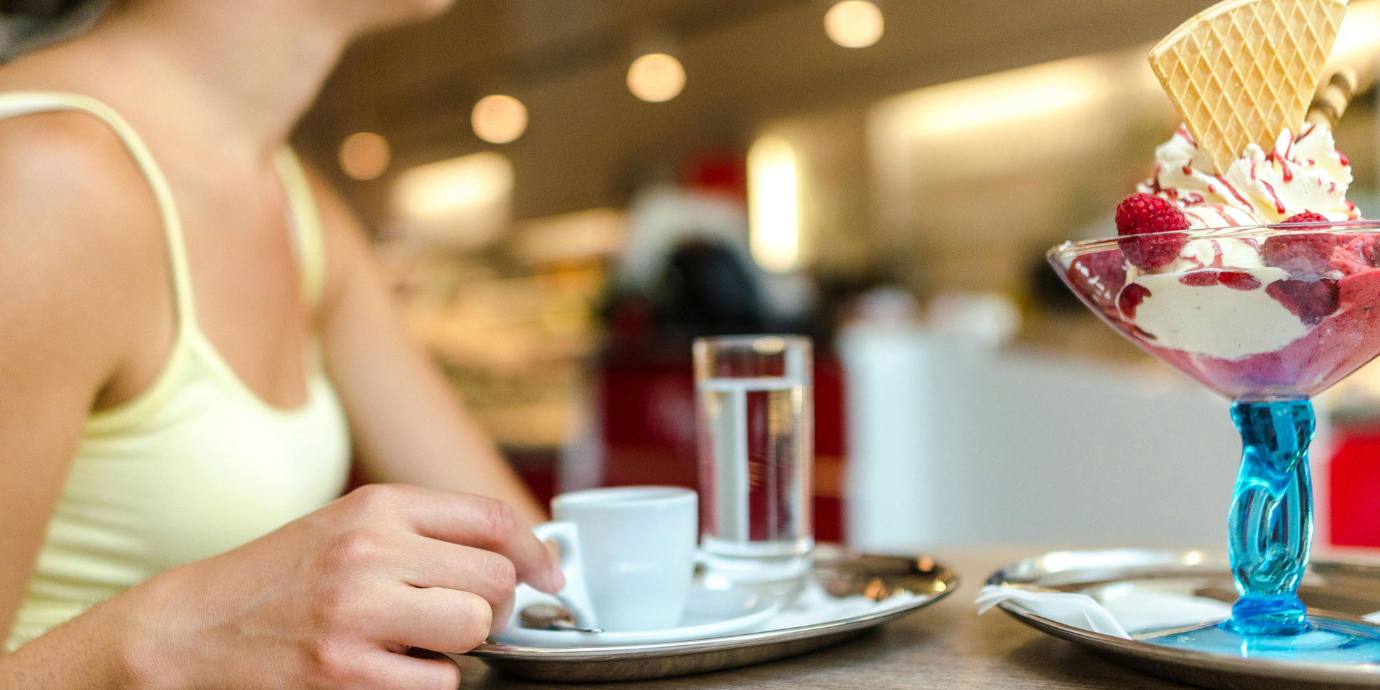 Someone enjoying a coffee and an ice cream sundae in a sunny cafe