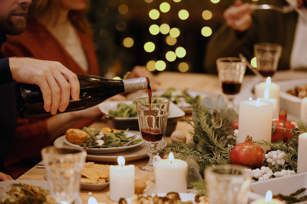 Close up of people enjoying a festive meal, pouring wine