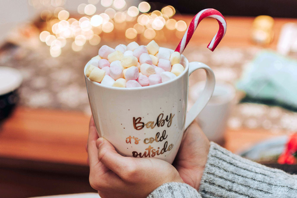 A hot chocolate with marshmallows and a candy cane