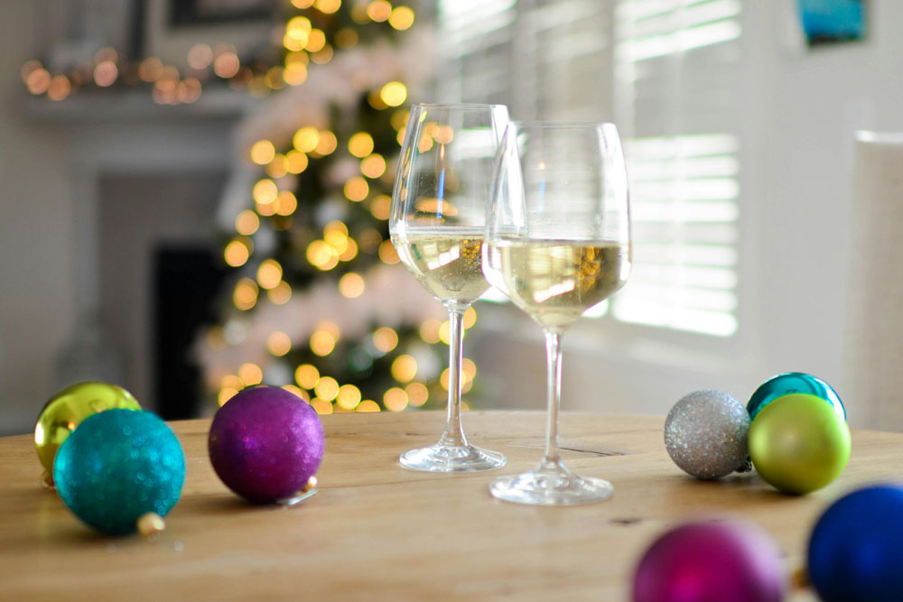 Two glasses of wne in front of a Christmas tree with coloured baubles