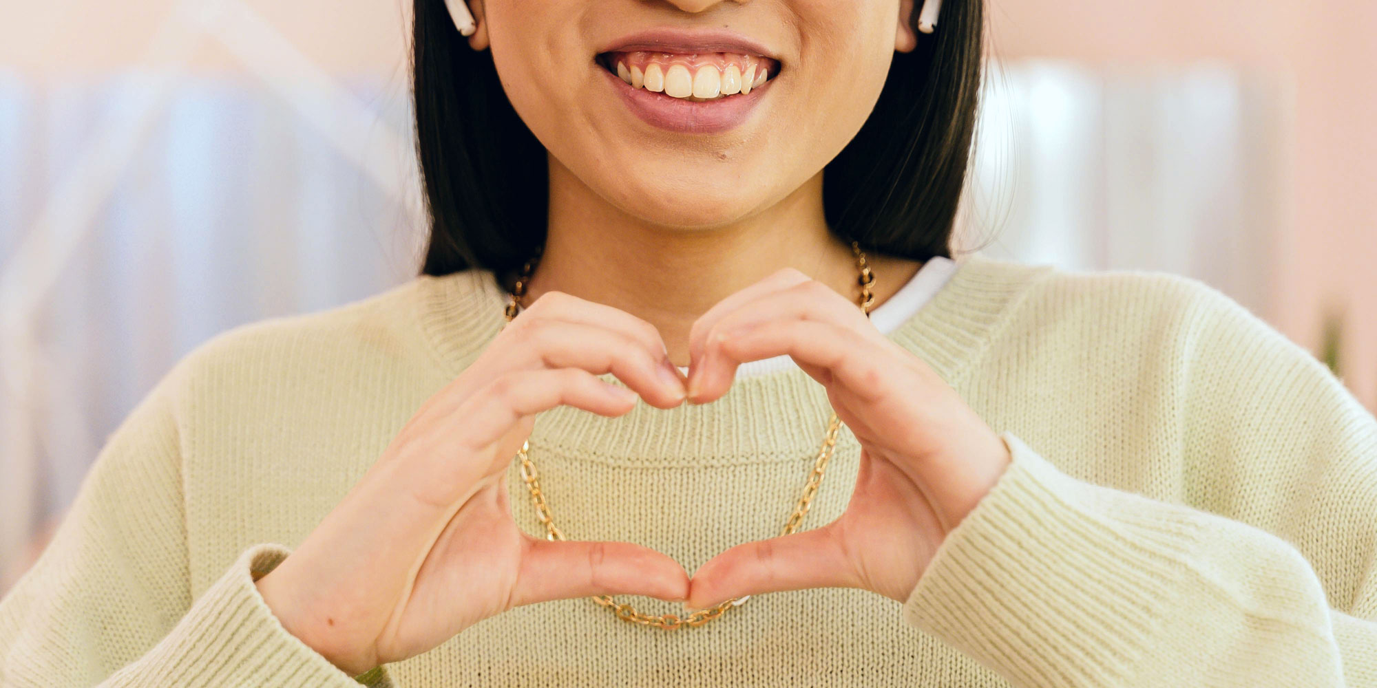 A lady with great gums signalling a heart with her hands