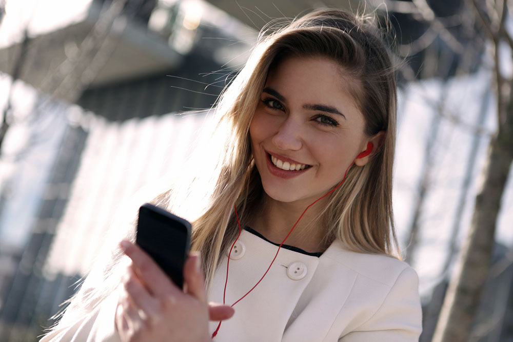 A smiling lady booking a dental appointment on her phone