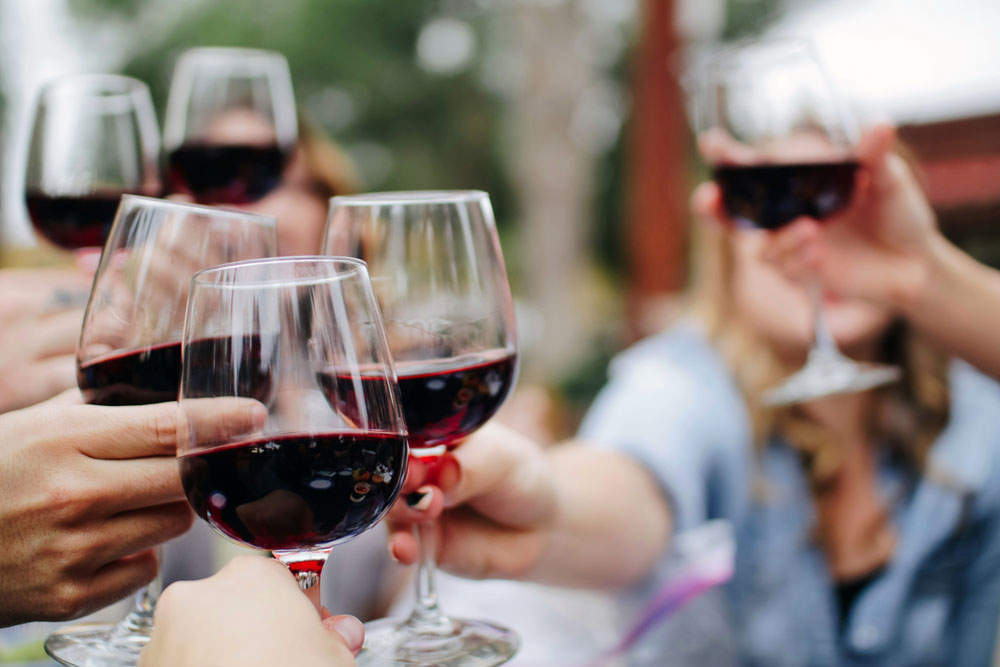 A group of people clinking red wine glasses (close up of glasses)